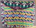 Handcrafted multicolored woolen clutch with button closure and vibrant patterns.